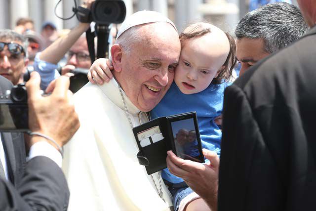 Pope Francis takes a photograph with a child